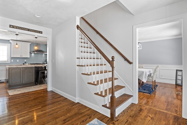 stairs featuring a wainscoted wall, a decorative wall, and wood finished floors