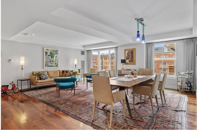 dining area featuring hardwood / wood-style flooring and a tray ceiling