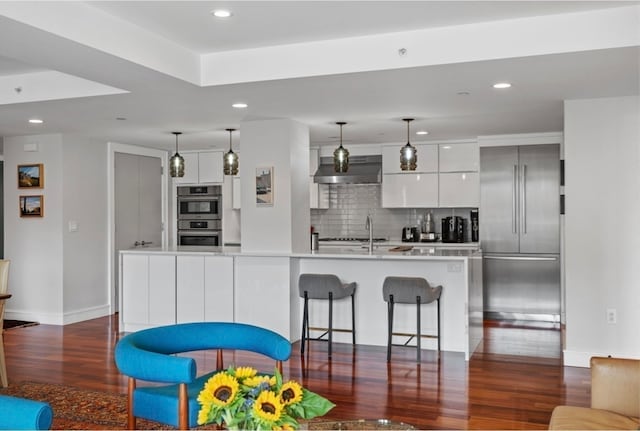 kitchen with a center island with sink, dark hardwood / wood-style flooring, white cabinets, and appliances with stainless steel finishes