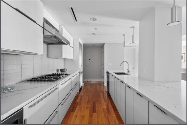 kitchen with sink, hanging light fixtures, dark hardwood / wood-style floors, white cabinetry, and stainless steel gas stovetop