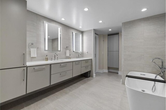 bathroom featuring a tub, vanity, and tile walls