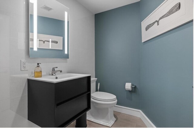 bathroom with tile patterned flooring, vanity, tile walls, and toilet