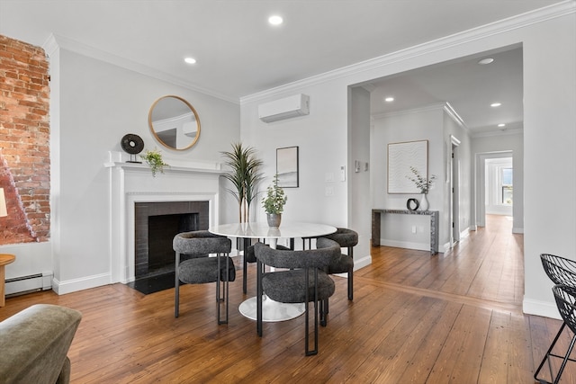 dining area with a brick fireplace, baseboard heating, crown molding, hardwood / wood-style flooring, and a wall mounted AC