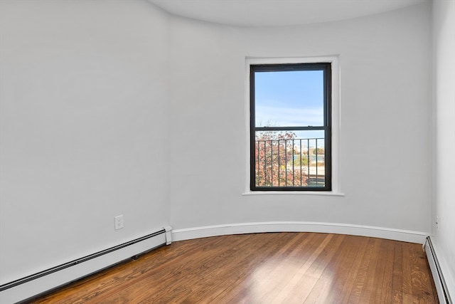 unfurnished room with a baseboard heating unit and hardwood / wood-style floors