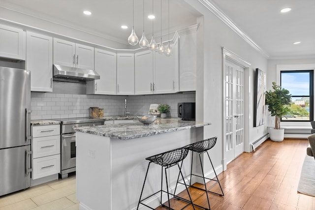 kitchen featuring appliances with stainless steel finishes, crown molding, white cabinets, and a baseboard heating unit