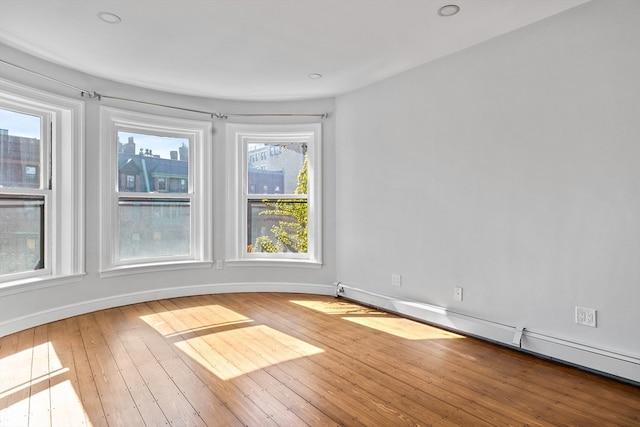 spare room with a baseboard heating unit and wood-type flooring