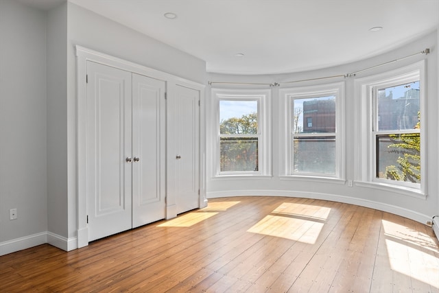 unfurnished bedroom with multiple windows and light wood-type flooring