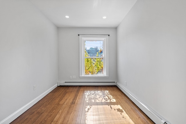 empty room with wood-type flooring and a baseboard heating unit