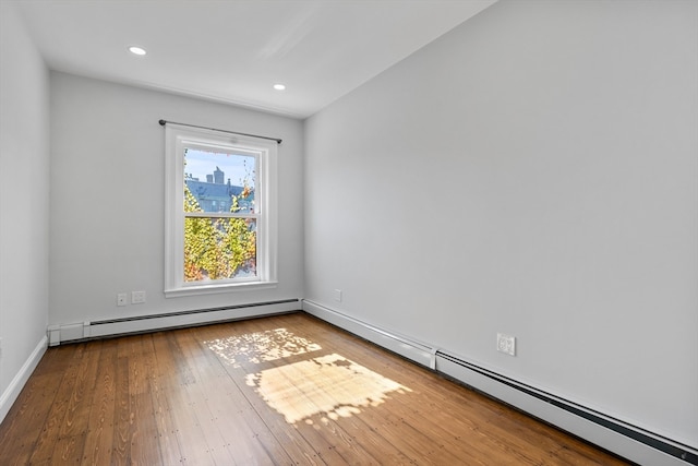 unfurnished room with wood-type flooring and a baseboard heating unit