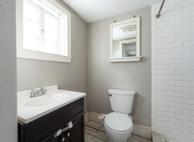 bathroom with vanity, tiled shower, and toilet