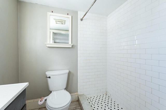 bathroom featuring vanity, toilet, and tiled shower