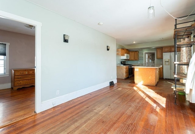 kitchen featuring white appliances, wood-type flooring, a kitchen bar, and a kitchen island