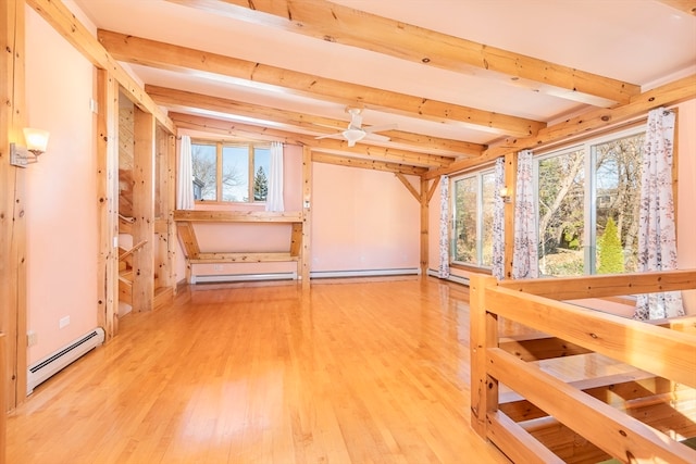 additional living space featuring ceiling fan, plenty of natural light, a baseboard radiator, and wood-type flooring