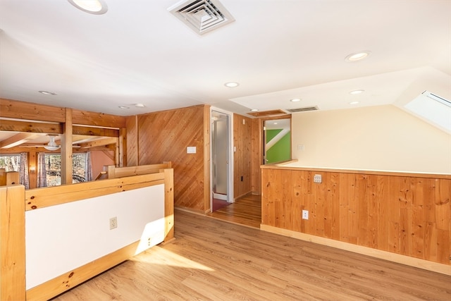 interior space with hardwood / wood-style floors, wooden walls, and vaulted ceiling with skylight