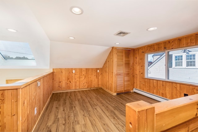 bonus room with hardwood / wood-style flooring, wood walls, and a baseboard heating unit