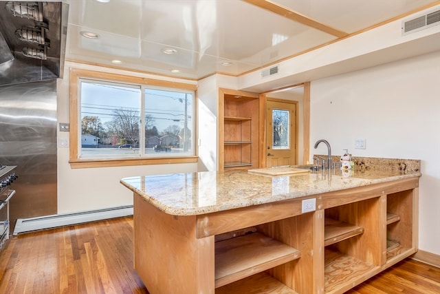 kitchen with light hardwood / wood-style floors, light stone countertops, a healthy amount of sunlight, and baseboard heating