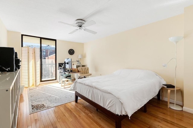 bedroom with a wall of windows, ceiling fan, and light hardwood / wood-style flooring