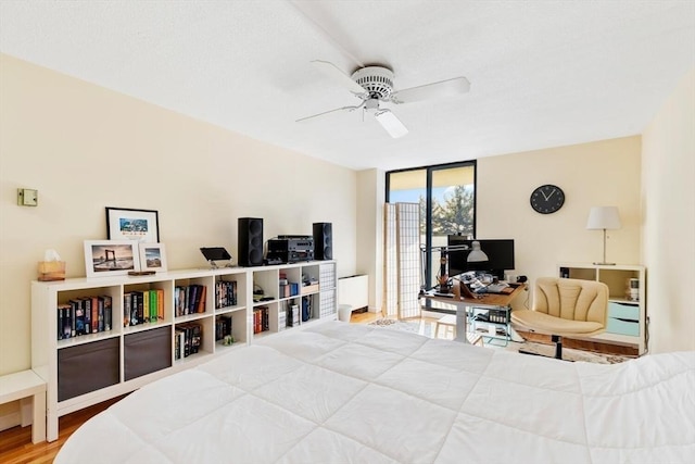 bedroom featuring hardwood / wood-style flooring, ceiling fan, access to exterior, and a wall of windows