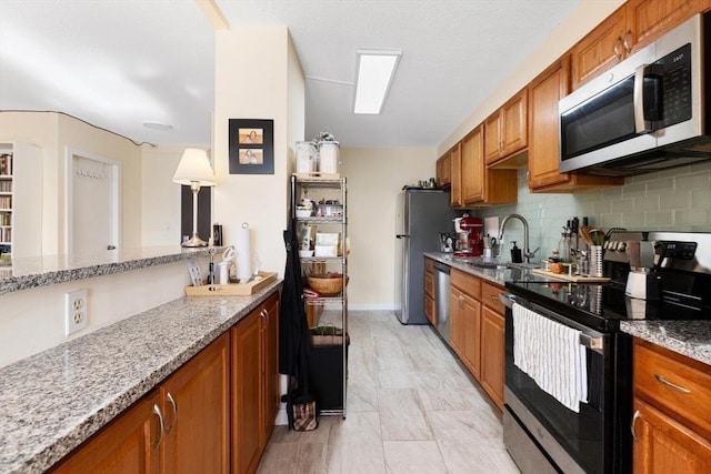 kitchen featuring light stone counters, sink, decorative backsplash, and stainless steel appliances