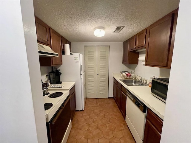 kitchen featuring sink, white appliances, light tile patterned floors, and a textured ceiling