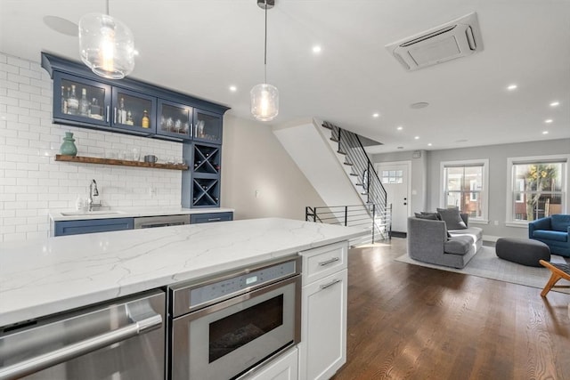 kitchen with dark hardwood / wood-style flooring, hanging light fixtures, blue cabinetry, and light stone countertops