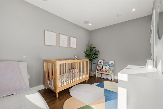 bedroom with a crib and dark hardwood / wood-style floors