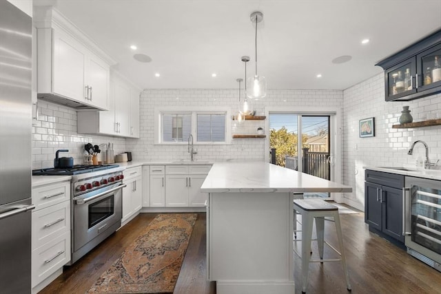 kitchen with sink, beverage cooler, white cabinets, and premium appliances