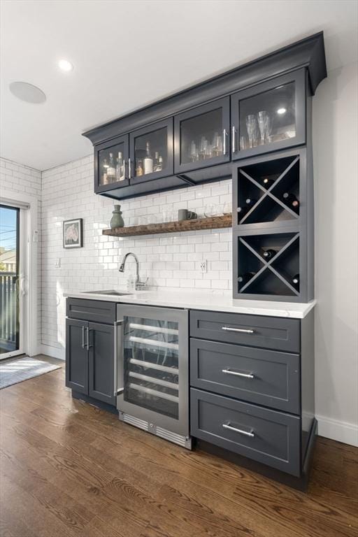 bar with wine cooler, sink, dark hardwood / wood-style flooring, gray cabinets, and backsplash