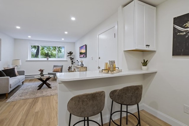 34 Bayview Ter Unit 3, Danvers, MA 01923 - kitchen featuring light wood-type flooring, white cabinets, a peninsula, a breakfast bar area, and recessed lighting