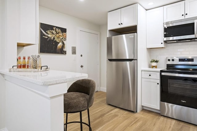 34 Bayview Ter Unit 3, Danvers, MA 01923 - kitchen featuring stainless steel appliances, a kitchen breakfast bar, light wood-type flooring, and white cabinets