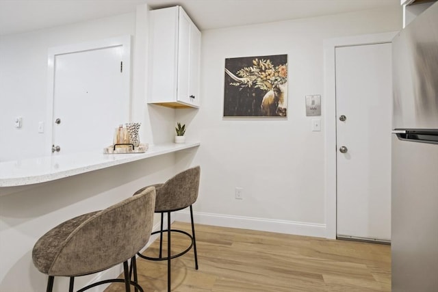 34 Bayview Ter Unit 3, Danvers, MA 01923 - kitchen with white cabinetry, a breakfast bar area, light wood-type flooring, and freestanding refrigerator