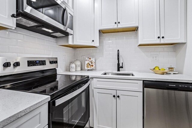 34 Bayview Ter Unit 3, Danvers, MA 01923 - kitchen featuring appliances with stainless steel finishes, a sink, white cabinetry, tasteful backsplash, and light stone counters