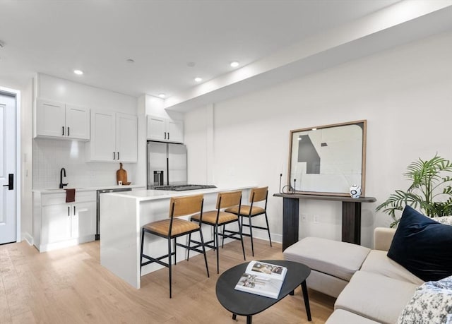 62 Haynes Unit 201, Boston, MA 02128 - kitchen with stainless steel appliances, a breakfast bar, light wood-type flooring, tasteful backsplash, and white cabinets