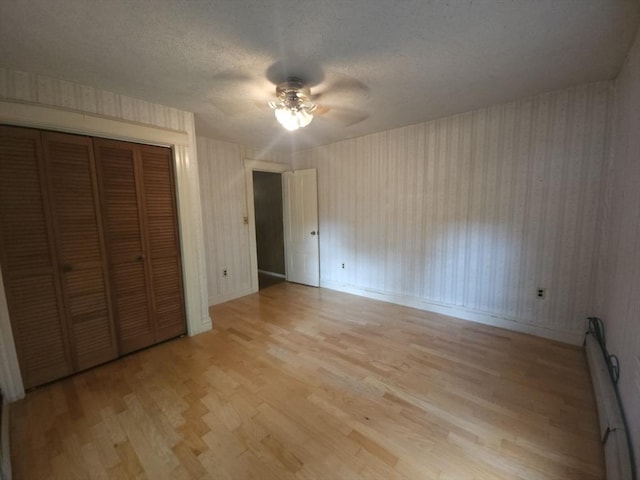 45 Circuit Ave E, Worcester, MA 01603 - unfurnished bedroom with light wood-style floors, a closet, baseboard heating, wallpapered walls, and a ceiling fan