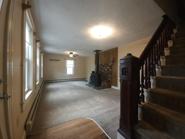 45 Circuit Ave E, Worcester, MA 01603 - unfurnished living room with a wood stove, light carpet, stairway, a textured ceiling, and baseboard heating