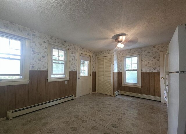 45 Circuit Ave E, Worcester, MA 01603 - empty room with a baseboard radiator, wainscoting, a textured ceiling, healthy amount of natural light, and wallpapered walls