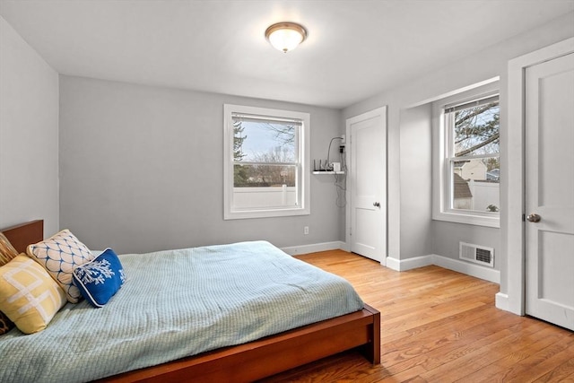 bedroom featuring wood finished floors, visible vents, and baseboards