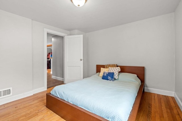 bedroom featuring visible vents, baseboards, and wood finished floors