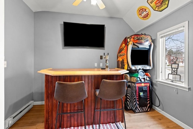 bar with a baseboard heating unit, lofted ceiling, a bar, and light wood-style flooring