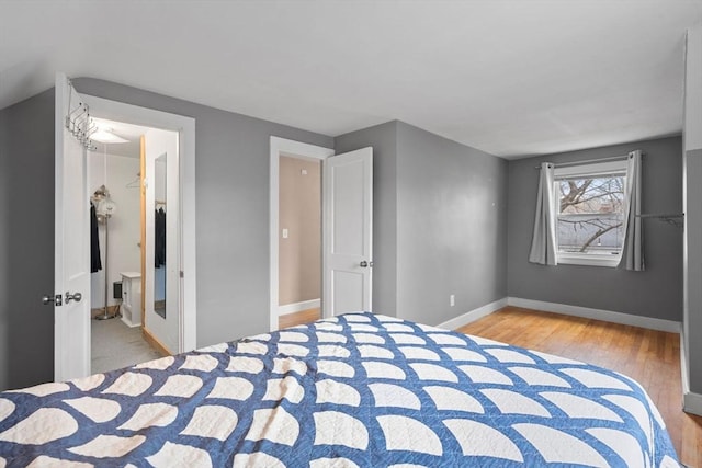 unfurnished bedroom featuring a spacious closet, baseboards, and wood finished floors