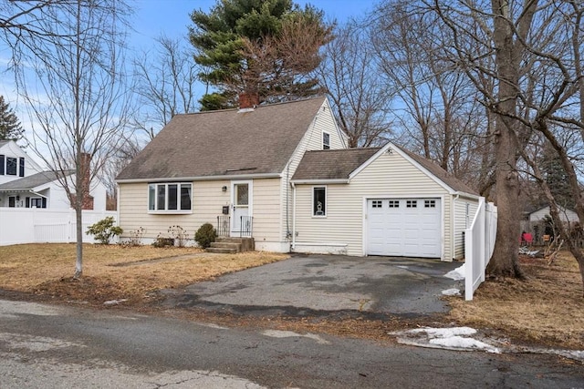 cape cod home with aphalt driveway, an attached garage, fence, and a shingled roof