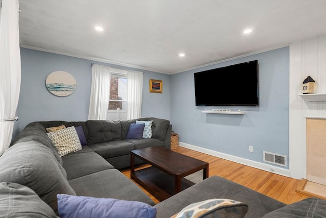 living room featuring visible vents, baseboards, wood finished floors, and ornamental molding