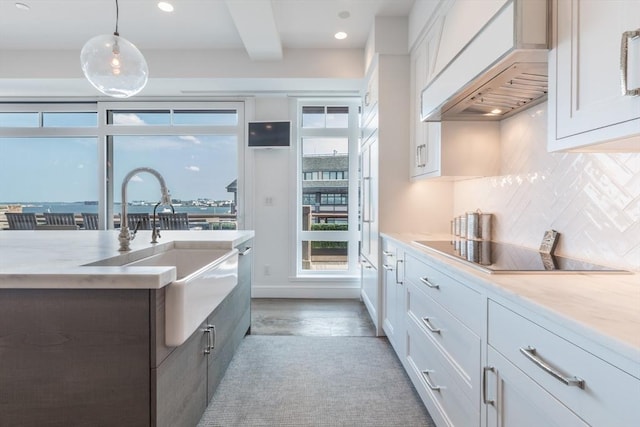 kitchen featuring pendant lighting, black electric cooktop, white cabinetry, and custom exhaust hood