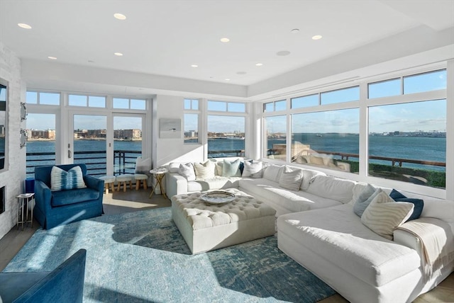 living room with a large fireplace, a water view, and wood-type flooring