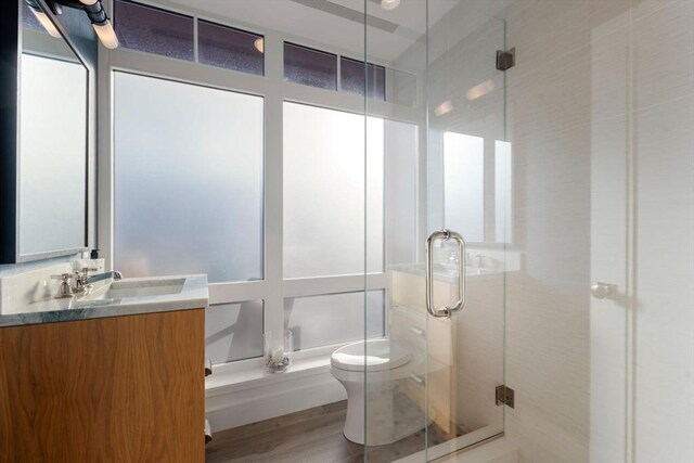 bathroom featuring hardwood / wood-style floors, vanity, toilet, and an enclosed shower