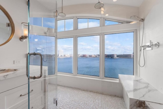 bathroom featuring a wealth of natural light, a shower with door, a water view, and vaulted ceiling