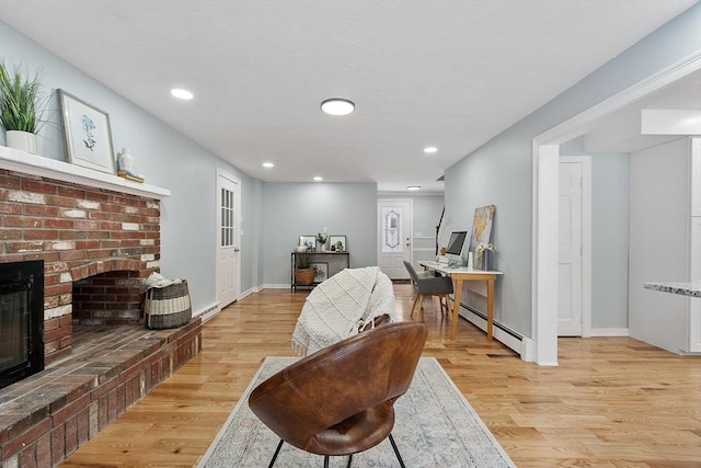 living area with recessed lighting, a fireplace, light wood-style floors, and a baseboard radiator