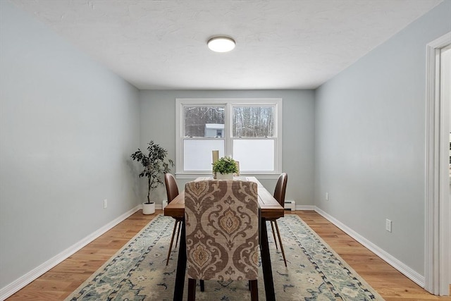 dining room with light wood-type flooring, baseboards, and baseboard heating