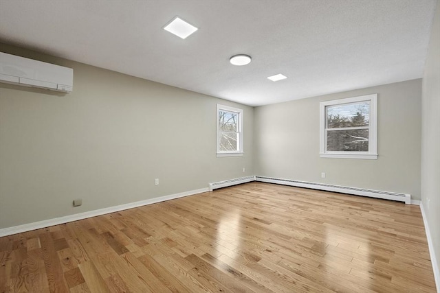 empty room with a baseboard heating unit, baseboards, wood finished floors, and a wall mounted AC