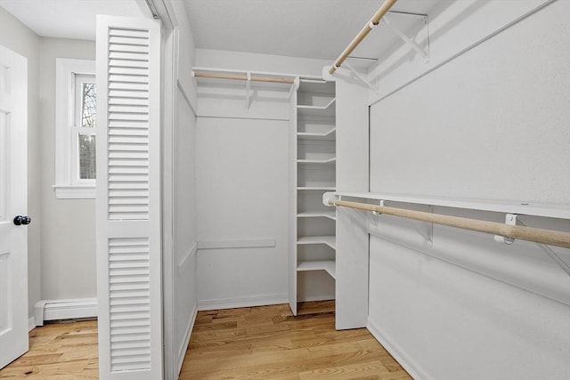 spacious closet with light wood-style floors and baseboard heating